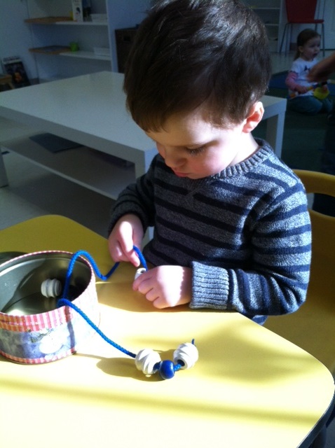 Montessori preschool child stringing beadss